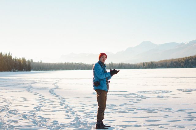 Man hiking through snowy landscape with mountains in background, showcasing outdoor adventure and exploring nature. Ideal for travel ads, winter sports promotions, and nature-themed content.