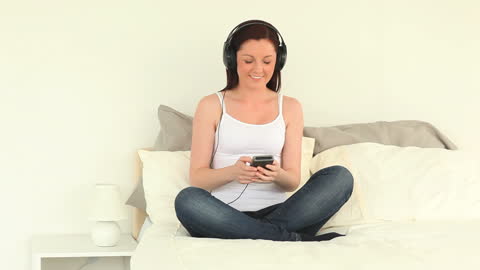 Smiling Woman Relaxing with Headphones on Bed