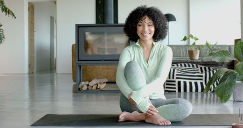 Woman Practicing Yoga in Modern Cozy Living Room with Fireplace