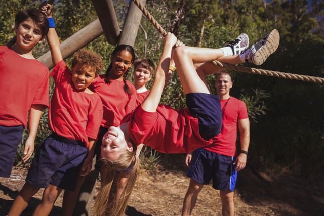 Kids climbing a traverse rope during obstacle course training in boot camp