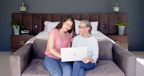 Senior Asian Mother and Daughter Bonding While Using Laptop on Sofa