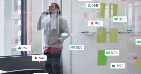 Startup founder calling while receiving social media notifications in glass meeting room