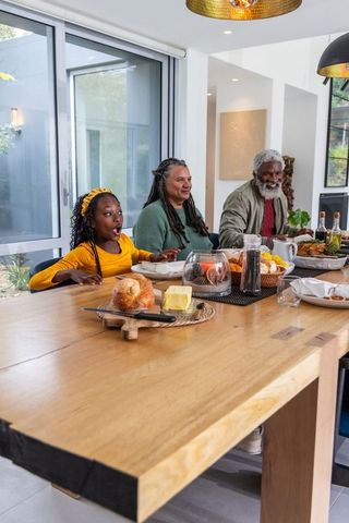 Multigenerational african american family sharing joyful breakfast around wooden table
