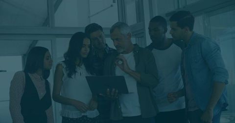 Diverse Team Collaborates on Laptop in Modern Office Environment