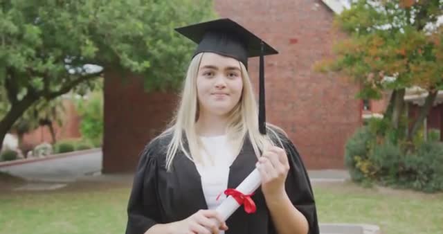 Teenage girl in graduation cap and gown holds diploma with a proud smile outdoors. Ideal for promoting academic achievement, education success, or celebrating graduation milestones in educational materials and social media announcements.