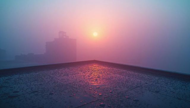Misty Sunrise Over Urban Rooftop with Water Droplets