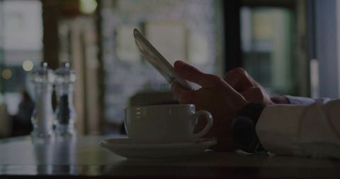 Business Professional Browsing on Smartphone at Cozy Cafe