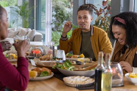 African american friends enjoying casual family dinner around sunlit wooden dining table
