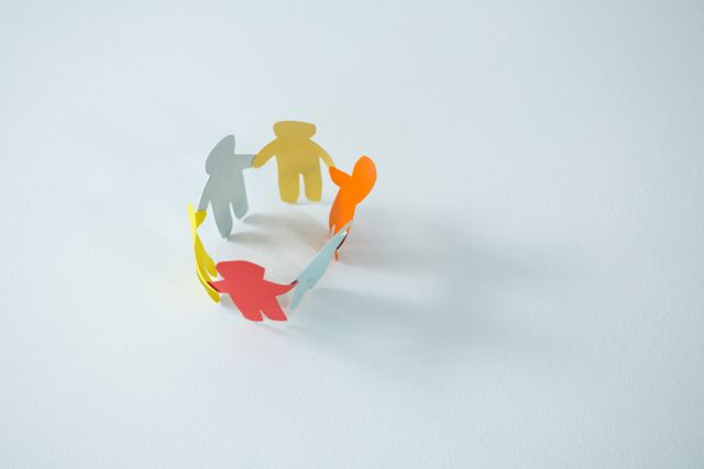 Circle of multicolored paper cut-out figures on white background