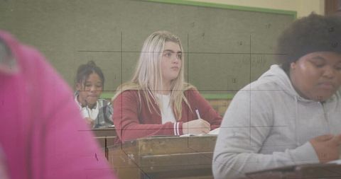 Focused blonde student writing in high school classroom