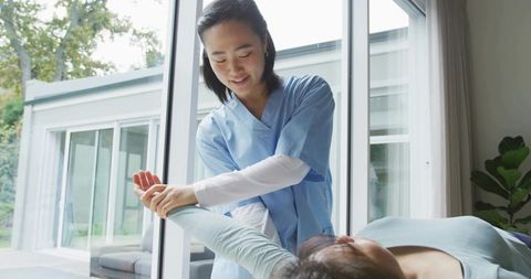 Physical therapist assisting patient with arm mobilization in sunlit rehabilitation room