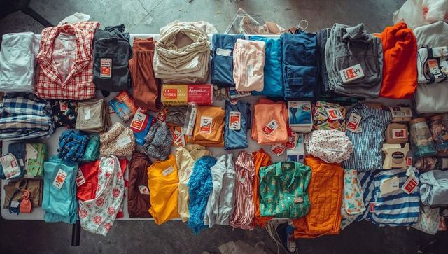 Laying out colorful folded clothing on table for garage sale donation and inventory