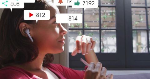 Content creator gazing through window holding stylus wearing earbud with floating social notificatio