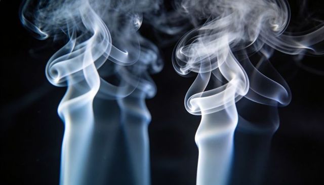 Rising smoke plumes curling into abstract loops over black backdrop with rim lighting