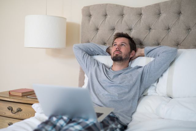 Man using laptop in bed at home