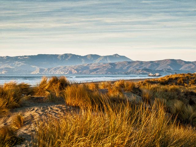 Sunset Over Scenic Coastal Dunes with Mountains in Background - Download Free Stock Photos Pikwizard.com