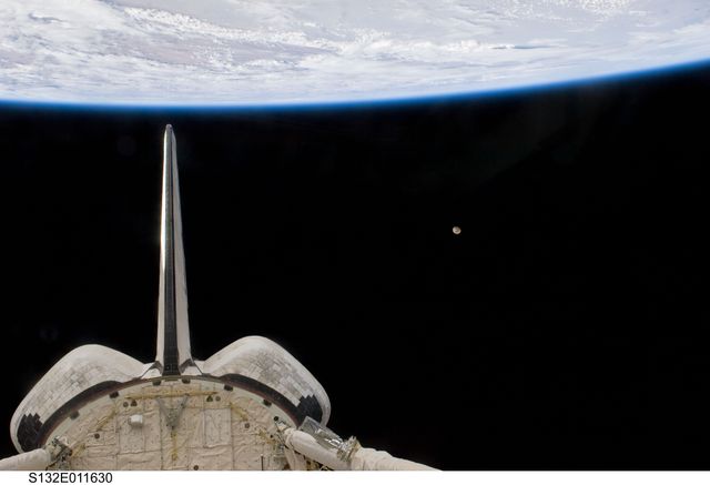 S132-E-011630 (25 May 2010) --- Space shuttle Atlantis’ vertical stabilizer, orbital maneuvering system (OMS) pods and aft payload bay; along with Earth’s horizon and the moon are featured in this image photographed by an STS-132 crew member on the shuttle during flight day 12 activities.