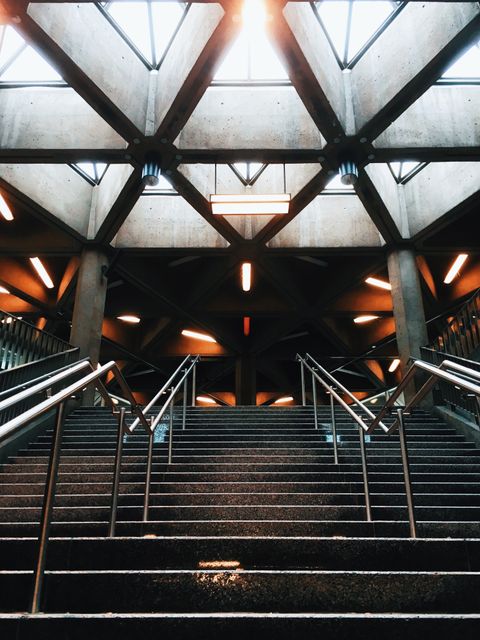 Subway station staircase with a geometric ceiling design creating a modern, urban atmosphere. Ideal for themes related to urban life, architecture, and design. Useful for projects on transportation, city exploration, and contemporary infrastructure.