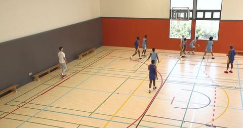 Team Practicing Basketball Under Sharp Coach Surveillance