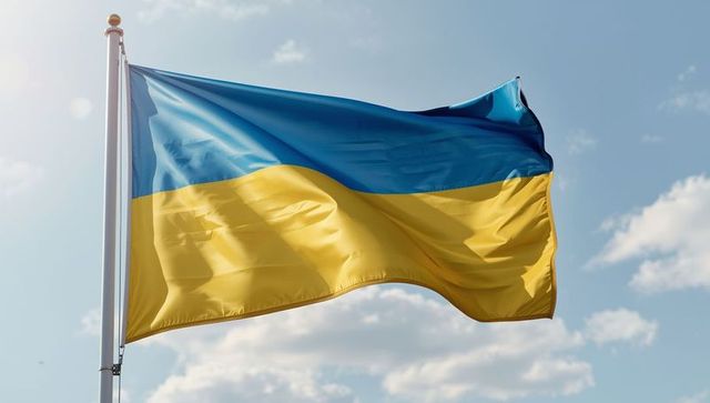 Ukraine flag waving in clear blue sky with sunlight