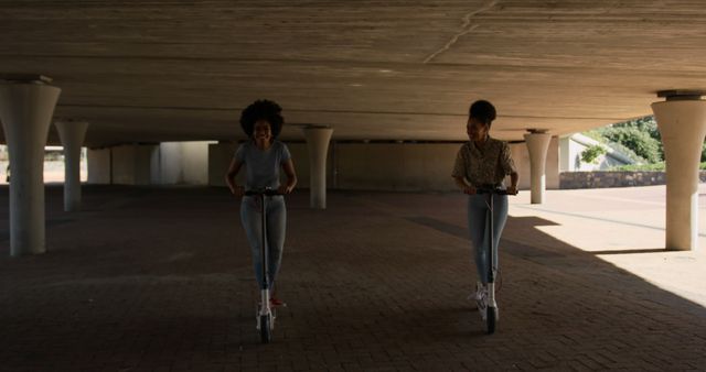 Two Young Women Riding Electric Scooters Under Bridge - Download Free Stock Images Pikwizard.com