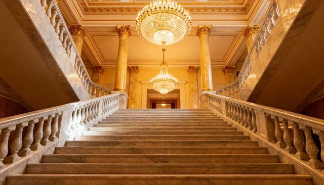 Grand marble staircase leading to crystal chandeliers in neoclassical palace
