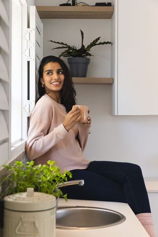 Woman Relaxing with Coffee at Kitchen Counter on Cozy Morning