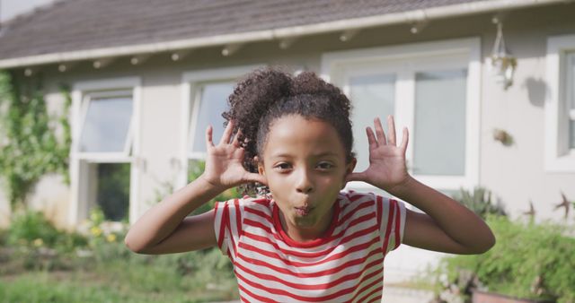 Portrait of happy african american girl making funny faces outside house in garden. Childhood, fun, summer, health and free time.