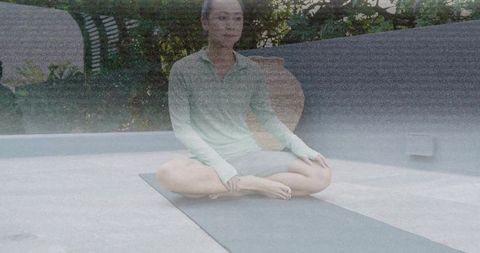 Woman practicing mindful breathwork and cross-legged yoga on rooftop terrace for wellness