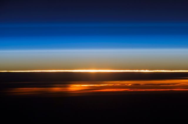 Stunning view of a sunset above the Earth's atmosphere captured from the International Space Station in 2006. Beautiful blend of colors depicting the atmospheric layers as the sun sets, showcasing the transition from day to night. Perfect for illustrating space exploration, atmospheric studies, and the beauty of outer space.