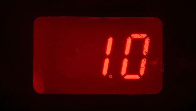 Red led seven-segment display displaying 10 with scratched window and glowing point