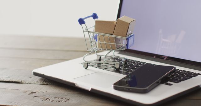 Mini shopping cart with boxes on a laptop represents online shopping and digital business. Suitable for illustrating ecommerce, technology, internet purchases, and small business marketing.