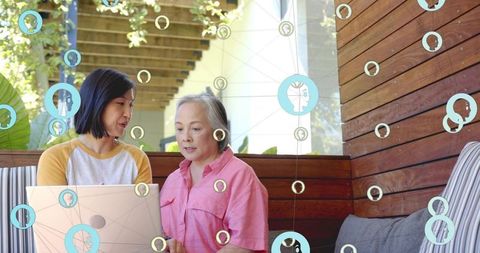 Daughter teaching mother using laptop on shaded patio bench with digital network overlay