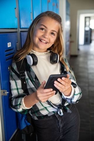 Happy Student With Smartphone and Headphones at School Locker