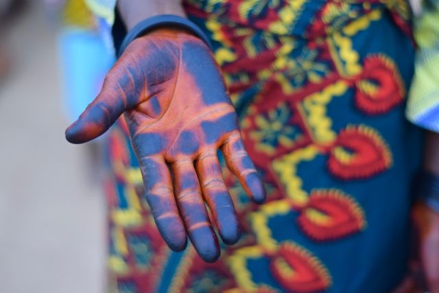 Hand with traditional henna tattoos wearing vibrant African attire. Useful for illustrations on African culture, traditional body art, cultural festivals, and fashion.