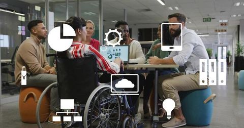Collaborating diverse team around laptop with wheelchair user and digital tech icons