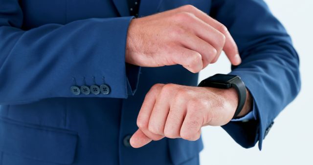 Close-up of a businessman in blue suit checking time on smartwatch. Suitable for use in articles about business technology, punctuality, modern gadgets in workplace, and professional attire.