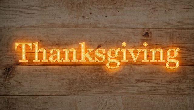 Glowing thanksgiving marquee sign with bulb lighting casting warm amber glow on wood panel