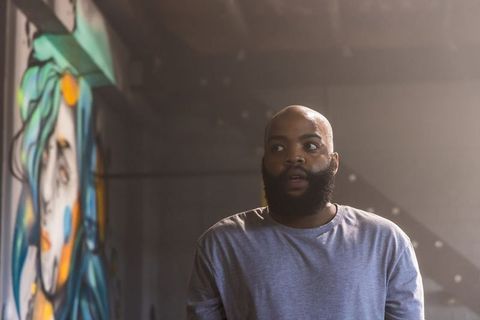 Moody industrial portrait of african man with beard looking right beside colorful mural