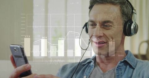 Middle-aged man analyzing mobile analytics with headset and smartphone, home dashboard visualization