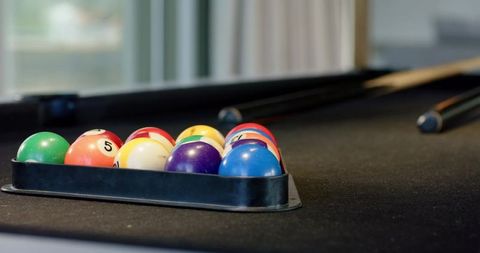 Racking pool balls on black felt table with cues ready for break, colorful closeup