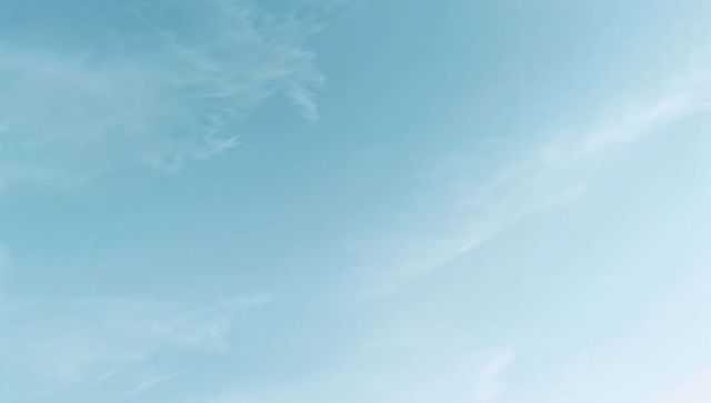 Pale blue sky with wispy cirrus clouds overhead soft gradient calm daylight background