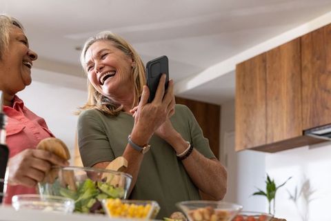 Senior Female Friends Cooking and Laughing in Kitchen