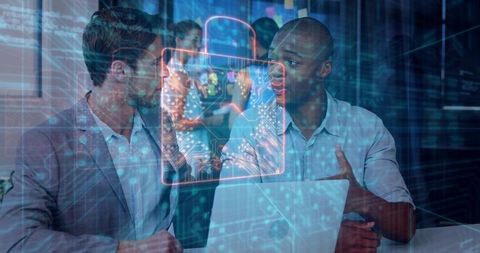Colleagues discussing AR data security with holographic circuit lock over laptop in office