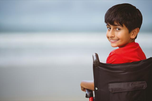 Digital composite of Portrait of boy sitting on wheelchair at beach