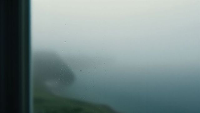 Moody foggy coast with water droplets on window pane