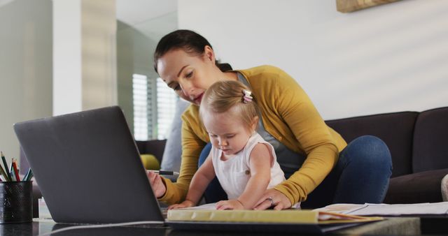Mother sits on a couch with a laptop, toddler on her lap, exemplifying multitasking and work-life balance. Great for articles on remote work, parenting tips, family life, and work-at-home setups. Can also be used for blogs about balancing career and family or advertisements for work-from-home tools and resources.