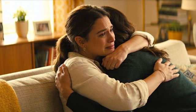 Woman hugging tearful friend on sofa comforting embrace in cozy living room moments