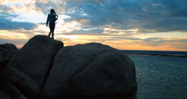 Silhouette of Woman Standing on Rock by Ocean During Sunset - Download Free Stock Images Pikwizard.com