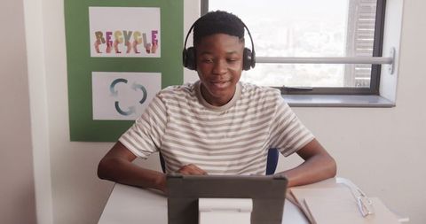 Teenage Boy Studying with Tablet and Headphones in Classroom